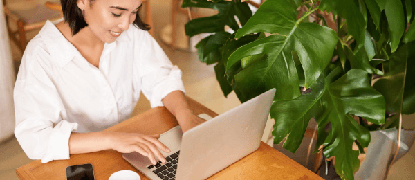 Young woman writing a job application essay on her laptop in a calm, focused setting - symbolizing preparation and professionalism.